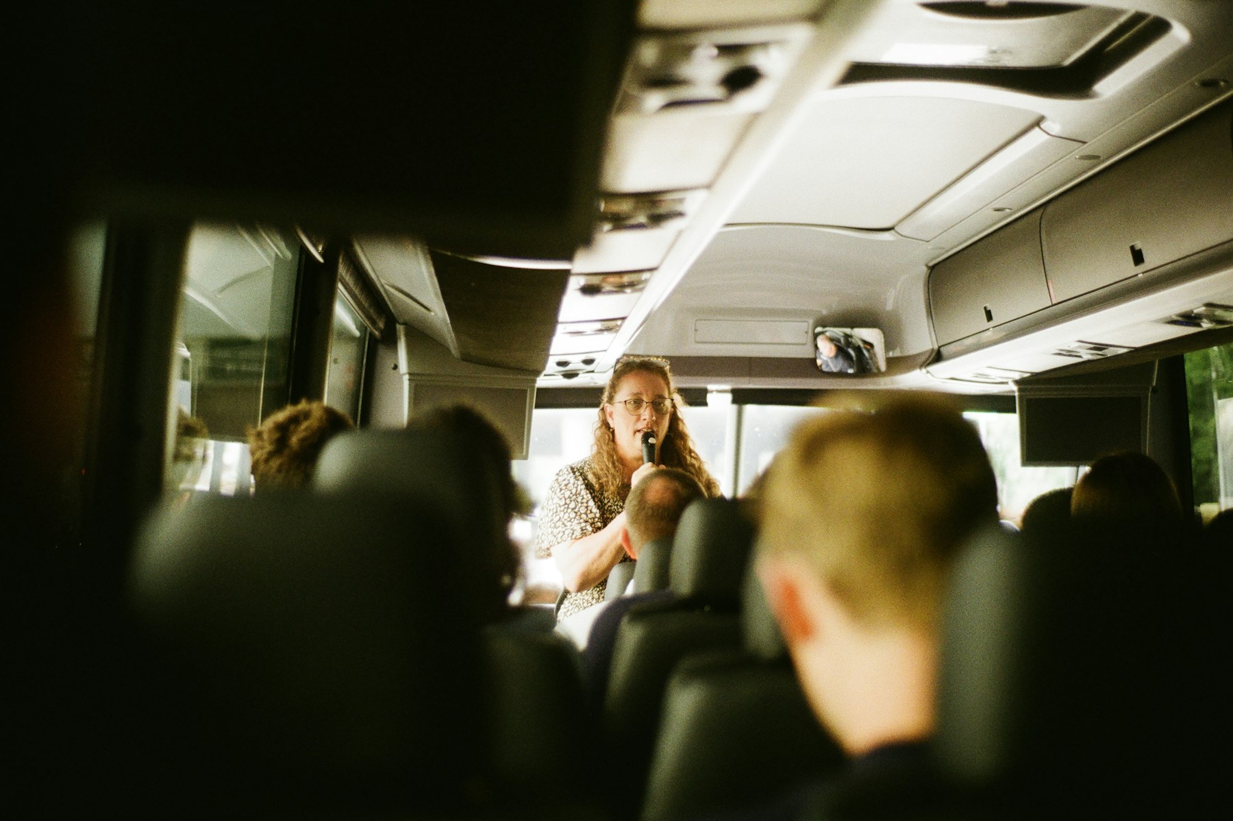 Guia conversando com os passageiros dentro do ônibus de turismo