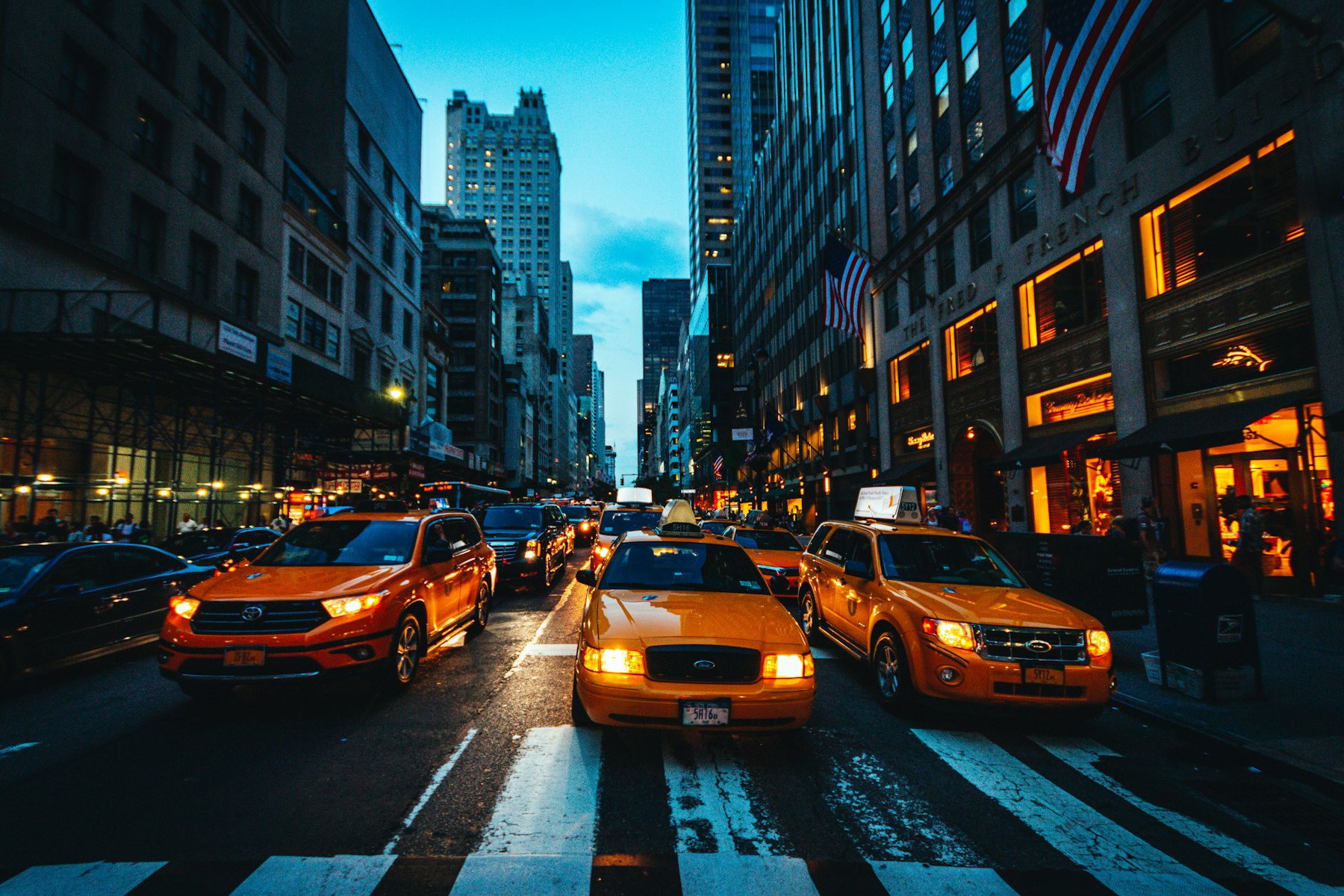 Táxis e tráfego em uma avenida de Manhattan ao entardecer